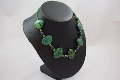 "Our Duckie N56 necklace is fun fun fun!  Featuring large fan shaped chrysocolla, dark teal jade, lime green agate, green Czech glass and brass African Trade Bead roundelles.  It is 18.25\" in length, closes with a brass toggle clasp and is ready to go strut around the office!  READY MADE BEADED NECKLACE * chrysocolla, jade, agate, African Trade Bead, Czech glass necklace * Measures approx. 18.25 inches in length * Ready to wear * Add a additional pair of Arc stud earrings -- see drop down menu Handmade Bohemian Green Emerald Necklace, Handmade Green Bohemian Emerald Necklace, Handmade Adjustable Green Emerald Necklace, Green Jade Beaded Necklaces, Green Chrysocolla Single Strand Necklace, Green Chrysocolla Gemstone Beads Jewelry, Green Chrysocolla Round Bead Necklaces, Green Chrysocolla Round Beads Necklace, Unique Green Natural Stone Necklace