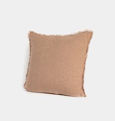 a beige pillow with fray edges on a white background