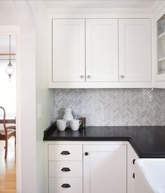 a kitchen with white cabinets and black counter tops in the center is featured on pinterest