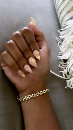 a woman's hand with some gold nail polish on it