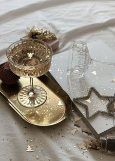 two wine glasses sitting on top of a tray with confetti and star decorations