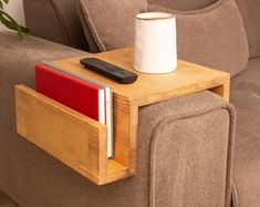 a wooden table with a remote control and a cup on it next to a couch