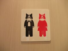 two stickers with cats on them sitting on a wall next to a toilet paper dispenser