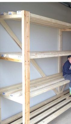 a man sitting on top of a wooden shelf next to another man standing in front of him