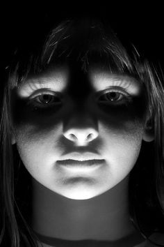 a woman's face is shown in black and white with the light coming through her eyes