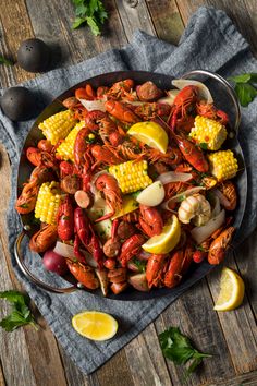 lobster, corn and potatoes on a platter with lemon wedges next to it