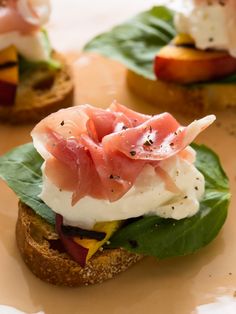 small sandwiches are topped with meat and cheese on top of green leafy breads