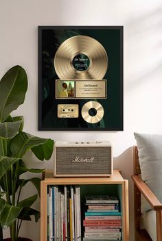 a gold record player sitting on top of a wooden table next to a plant and bookshelf