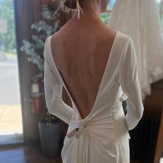 the back of a woman's wedding dress in front of a window