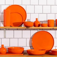 orange plates and bowls are arranged on the shelf