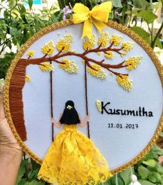 a woman in a yellow dress is hanging on a tree with the name kusumtha