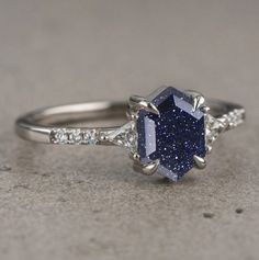 a blue and white diamond ring with diamonds on the side, set in 18k white gold