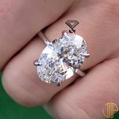 a close up of a person's hand holding a ring with a diamond on it