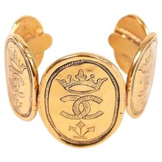 This is a rare 1987 Chanel 24k gold plated coin cuff bracelet comprised of a single oval gold coin at center front w/two additional coins on either side in descending size. Bracelet is stamped at the interior gold cartouche as collection 26 - from the era when Victoire de Castellane was head jewelry designer at Chanel. Bracelet fits snugly on the wrist and is an optimal fit for a smallish size wrist. In excellent condition with minor/hard to see scratches at the surface of the frontal coins as w Victoire De Castellane, Chanel Bracelet, Chanel Boutique, Head Jewelry, Gold Interior, Chanel Vintage, Gold Coin, Jewelry Designer, Cc Logo