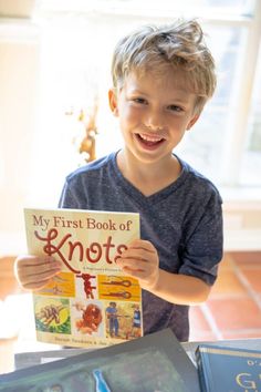 a young boy holding up a book about knots