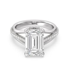 an emerald cut engagement ring with diamond accents on the band and side stones in white gold