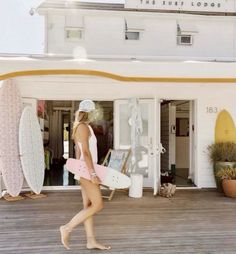 a woman is walking on the boardwalk with her surfboard