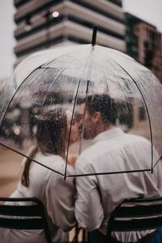 two people sitting under an umbrella in the rain