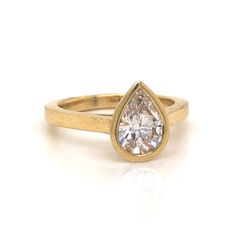 a yellow gold ring with a pear shaped diamond in the center, on a white background