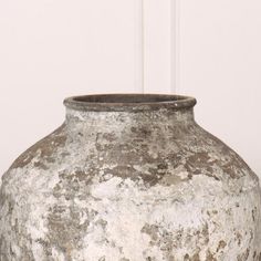 an old gray vase sitting on top of a wooden table next to a white wall