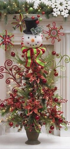 a decorated christmas tree with a snowman on top and ornaments around the fireplace mantel