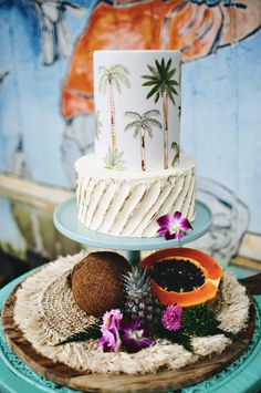 a three tiered cake sitting on top of a blue plate next to a painting