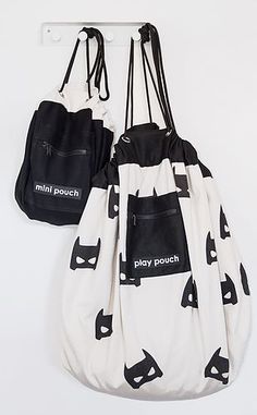 two black and white bags hanging from hooks on the wall, one with cat print