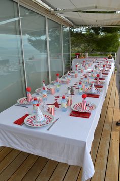 a long table is set up with red and white striped paper cups, plates and napkins