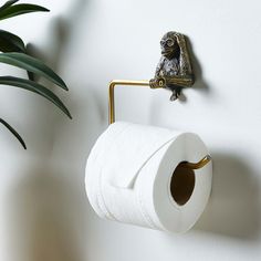 a toilet paper roll hanging on a wall next to a potted plant