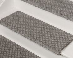 two gray rugs sitting on top of a white stair case next to each other