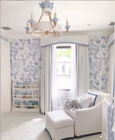 a baby's room with blue and white wallpaper, a crib, and a chandelier