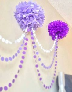 two purple pom - poms hanging from the side of a wall with beads