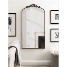 a large mirror sitting on top of a wall next to a white chair and pictures