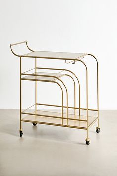 a gold serving cart with three trays on wheels