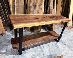 a wooden table with black metal legs and shelves in front of some wood planks