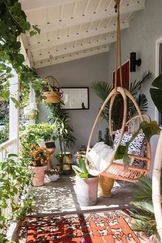 a porch with potted plants on it and a hanging hammock in the middle