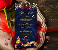 a red rose sitting on top of a table next to a blue and gold wedding card