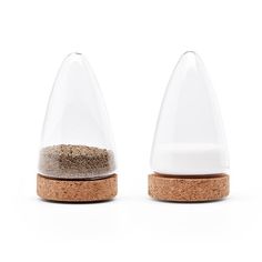 two salt and pepper shakers sitting next to each other on top of a white surface