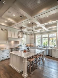 a large kitchen with white cabinets and wood flooring on the walls, along with an island that has stools for four