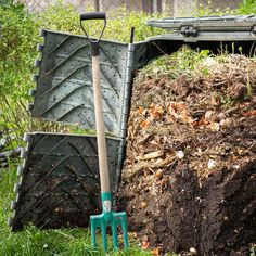 a pile of dirt and shovels next to a dumpster in the grass near some bushes