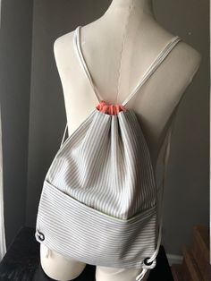 a white and gray striped bag sitting on top of a mannequin