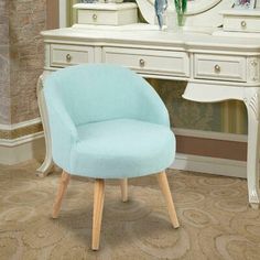 a light blue chair sitting in front of a white desk with a mirror on it