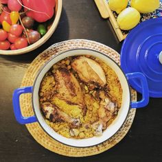 a pot filled with food sitting on top of a table next to bowls of fruit and vegetables