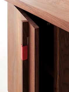 an open wooden cabinet with red tape sticking out of it