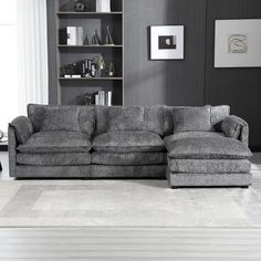 a large gray couch sitting in a living room next to a book shelf