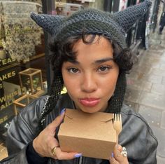 a woman with horns on her head holding a box