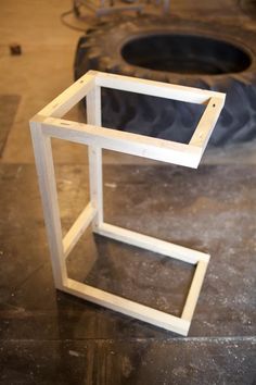 a wooden frame sitting on top of a floor next to a tire