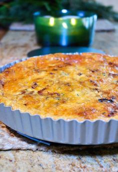 a quiche pie sitting on top of a table next to a green lit candle