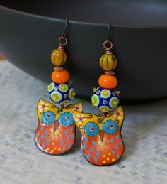 Whimsical owl earrings featuring delightful orange, yellow and blue enamel charms. I love their big mesmerizing eyes. They are topped with spotted blue, green and yellow lampwork beads, bright orange glass spacers, copper beads and yellow Czech glass beads. These earrings measure 2 3/4 inches in total length and hang on niobium earring hooks. Return to shop: bstrung.etsy.com More links where you can find me: Facebook: http://www.facebook.com/bstrung Pinterest: http://pinterest.com/bstrung Instag Nickel-free Orange Enamel Earrings, Orange Enamel Earrings Nickel Free, Artsy Orange Drop Earrings, Hand Painted Orange Earrings As Gift, Artistic Orange Dangle Jewelry, Unique Orange Metal Earrings, Artistic Orange Jewelry With Matching Earrings, Orange Enamel Earrings As A Gift, Orange Enamel Earrings For Gifts