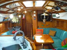 the inside of a sailboat with blue couches and wooden tables on it's sides